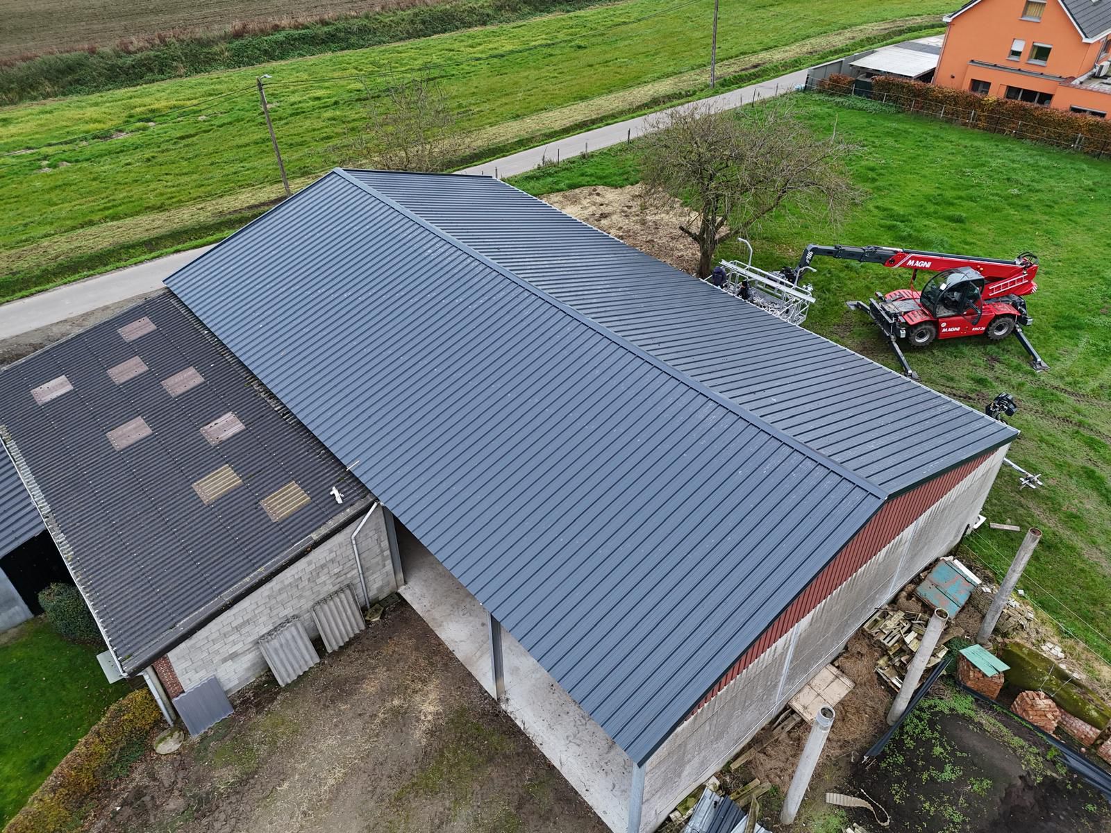 Loods met nieuw geplaatste dakplaten naast het oude dakdeel